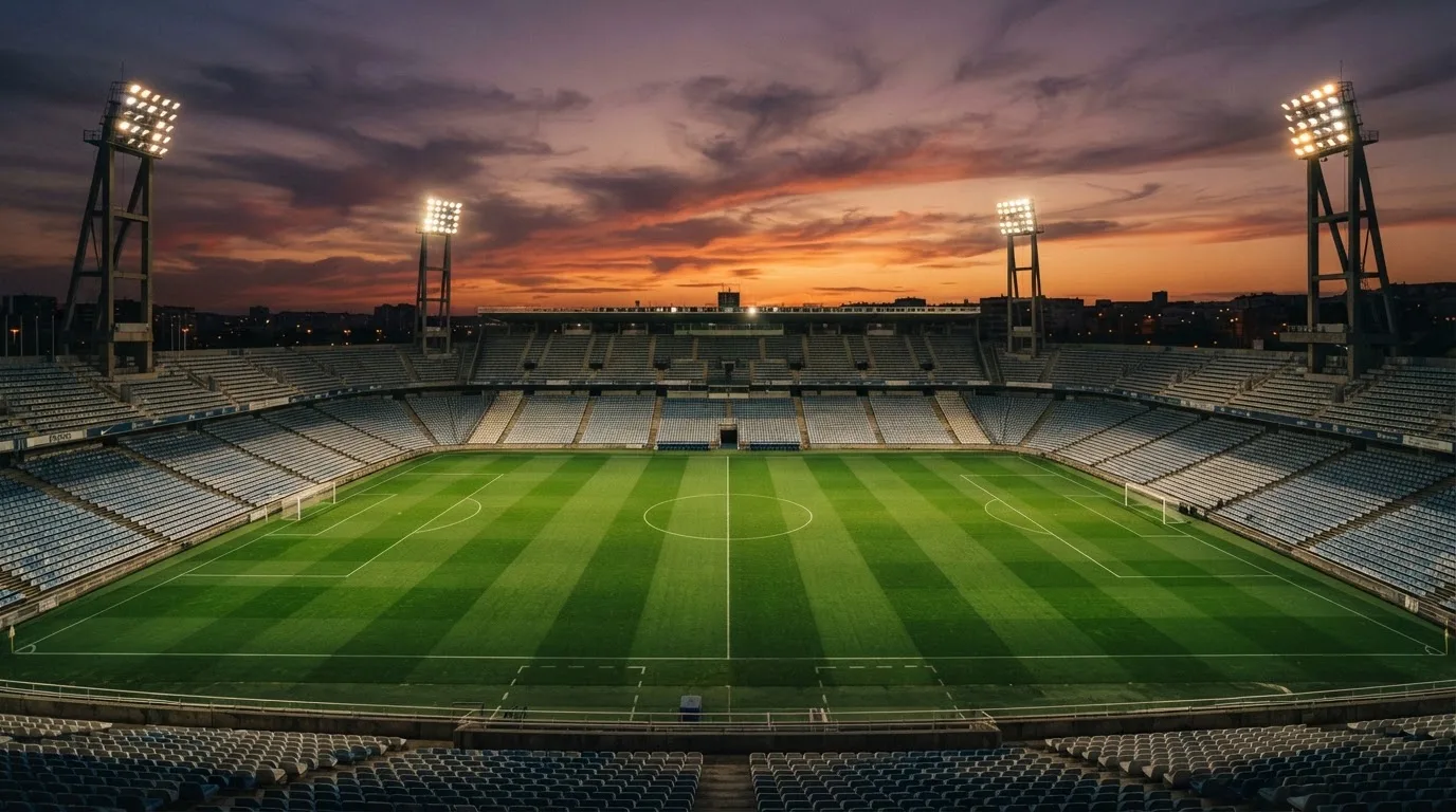 Un estadio de fútbol vacío con torres de iluminación al atardecer