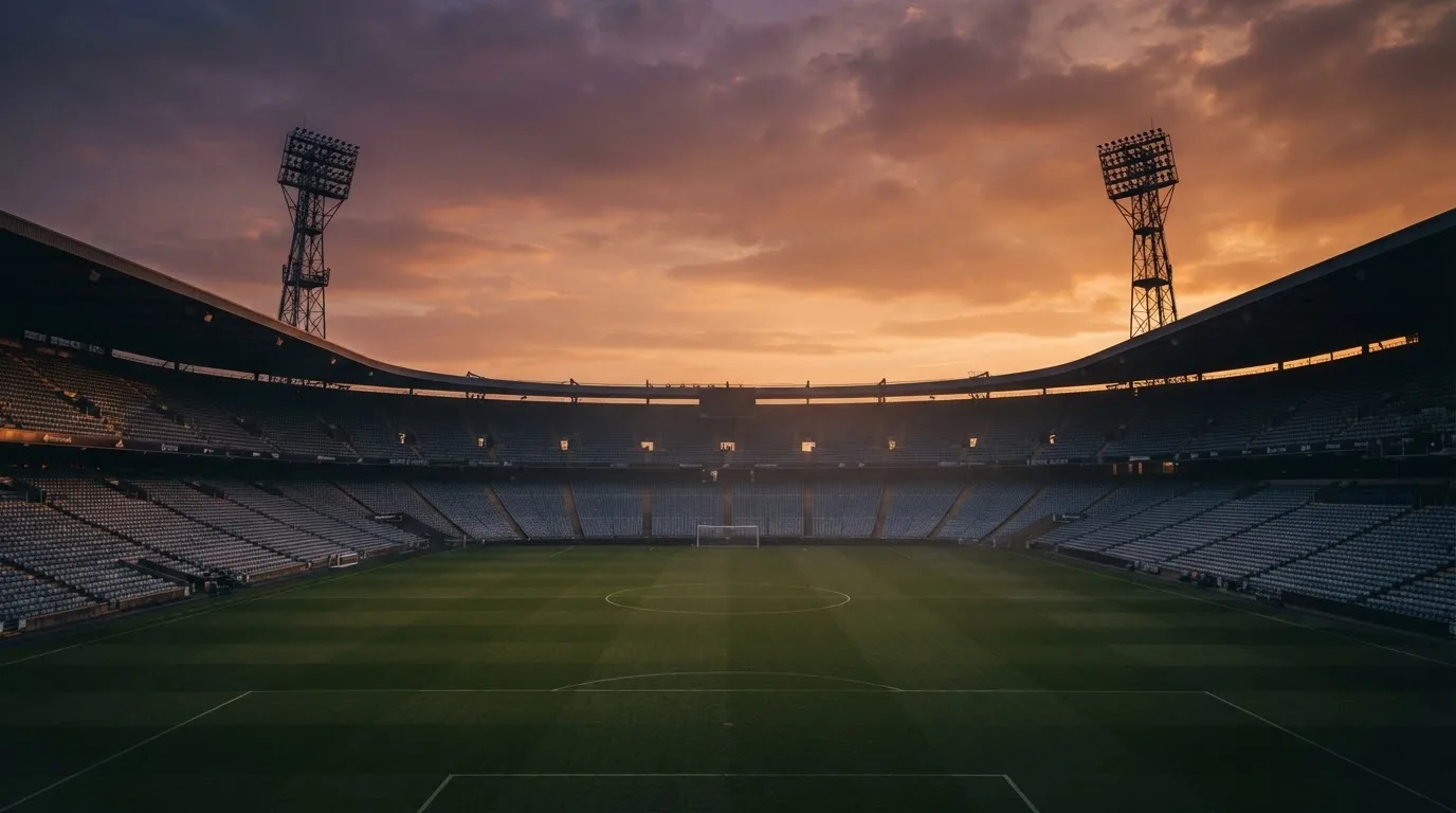 Un estadio de fútbol vacío con torres de iluminación al atardecer