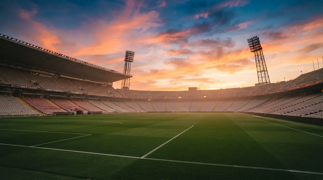Un estadio de fútbol vacío con torres de iluminación al atardecer
