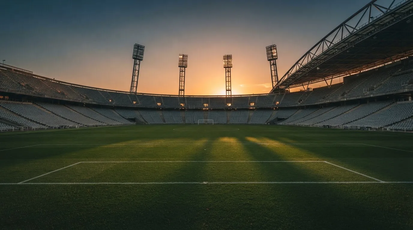 Un estadio de fútbol vacío con torres de iluminación al atardecer
