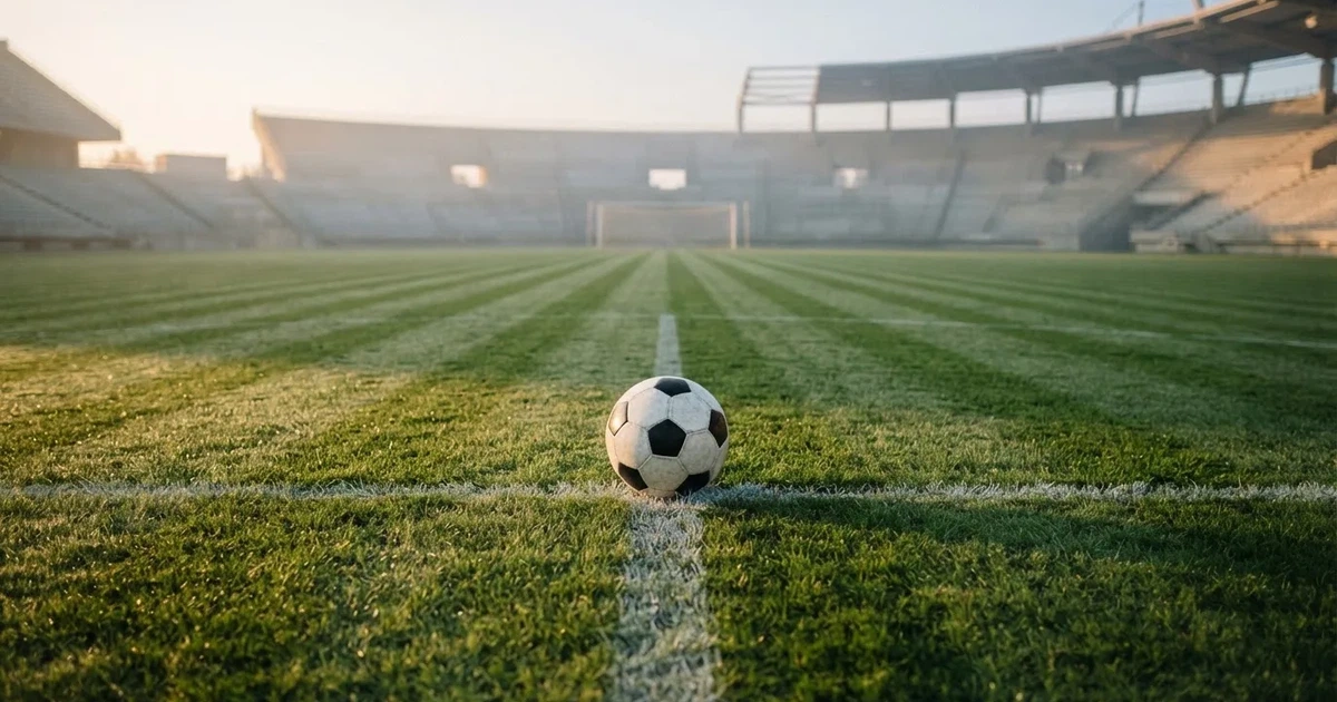 Un balón en el punto central de un campo de césped a la luz de la mañana