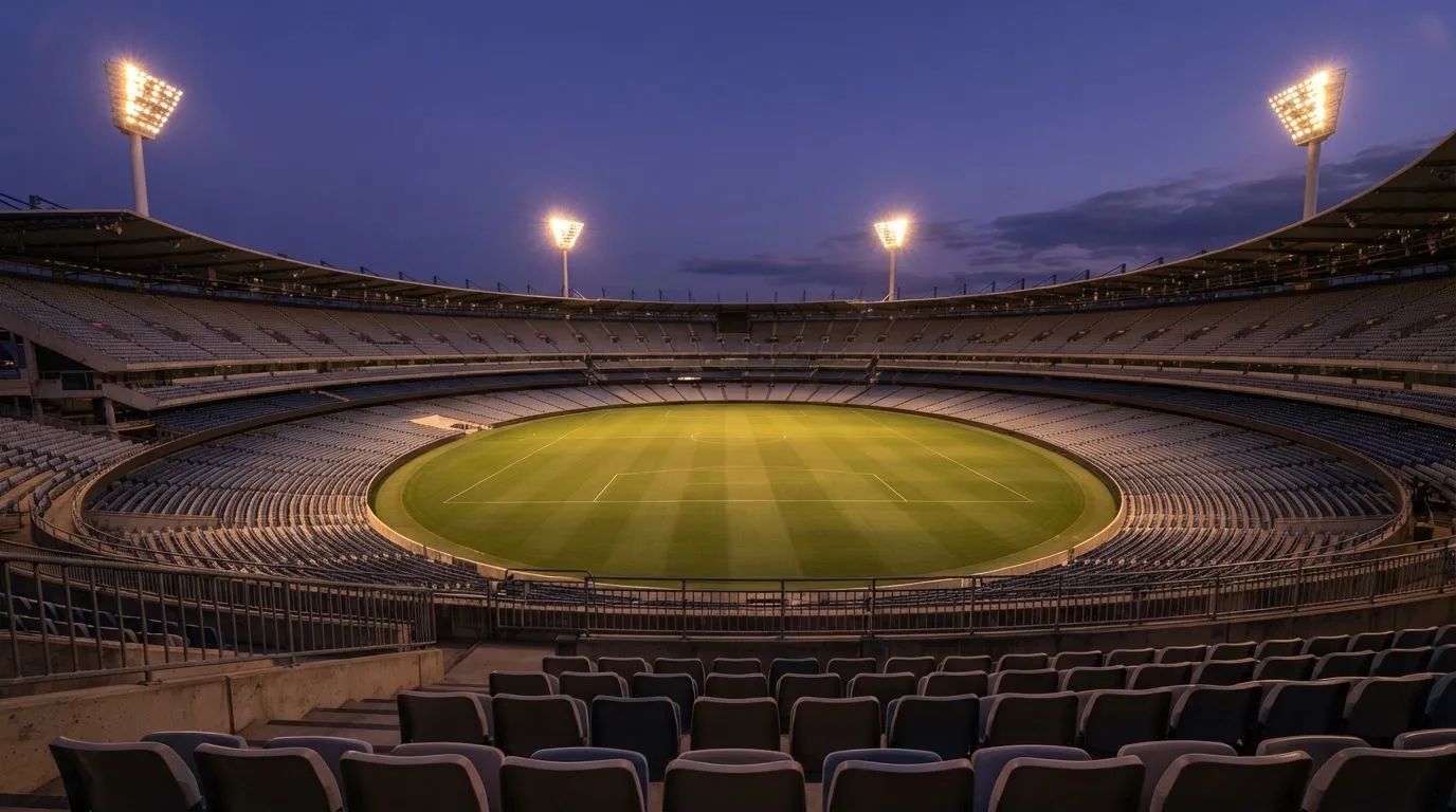 Un estadio de fútbol vacío con torres de iluminación al atardecer
