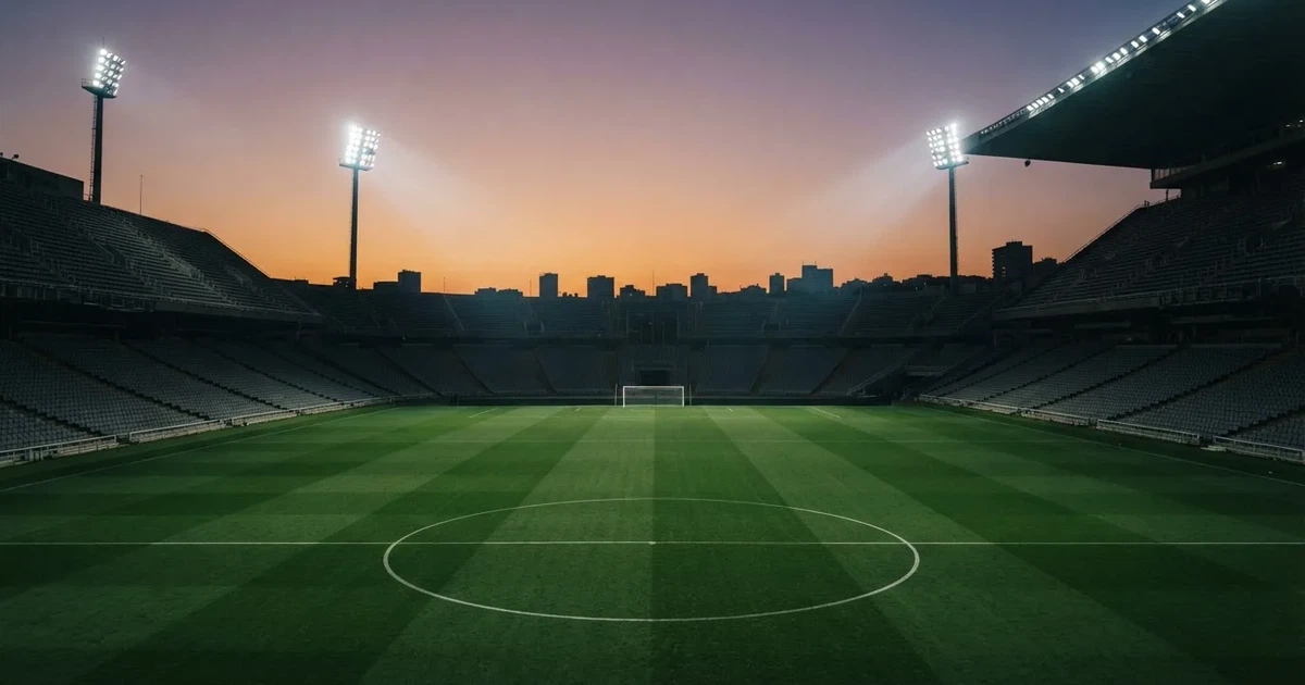 Un estadio de fútbol vacío con torres de iluminación al atardecer