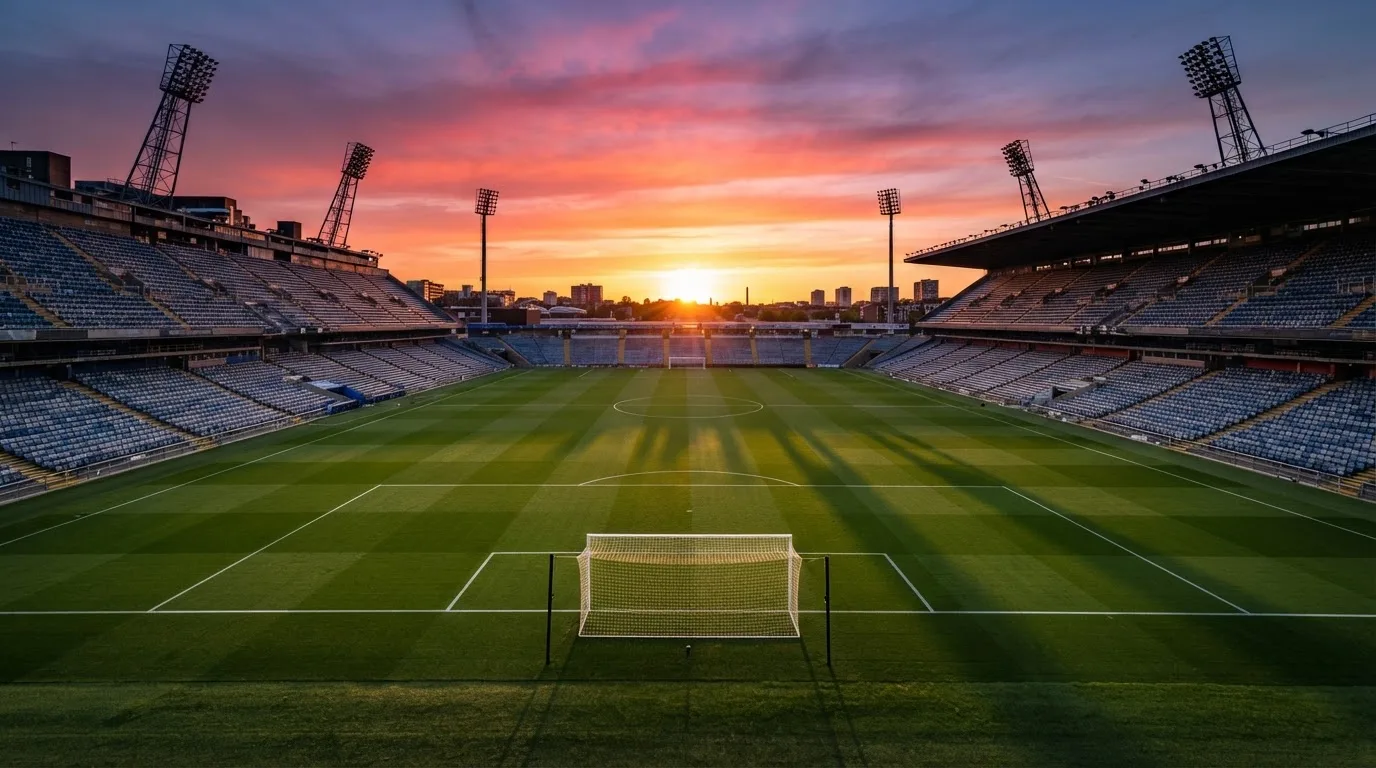 Un estadio de fútbol vacío con torres de iluminación al atardecer