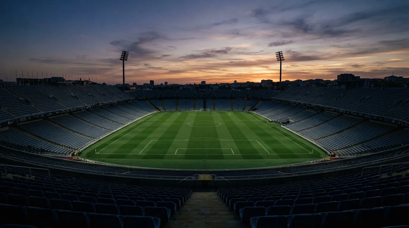 Un estadio de fútbol vacío con torres de iluminación al atardecer