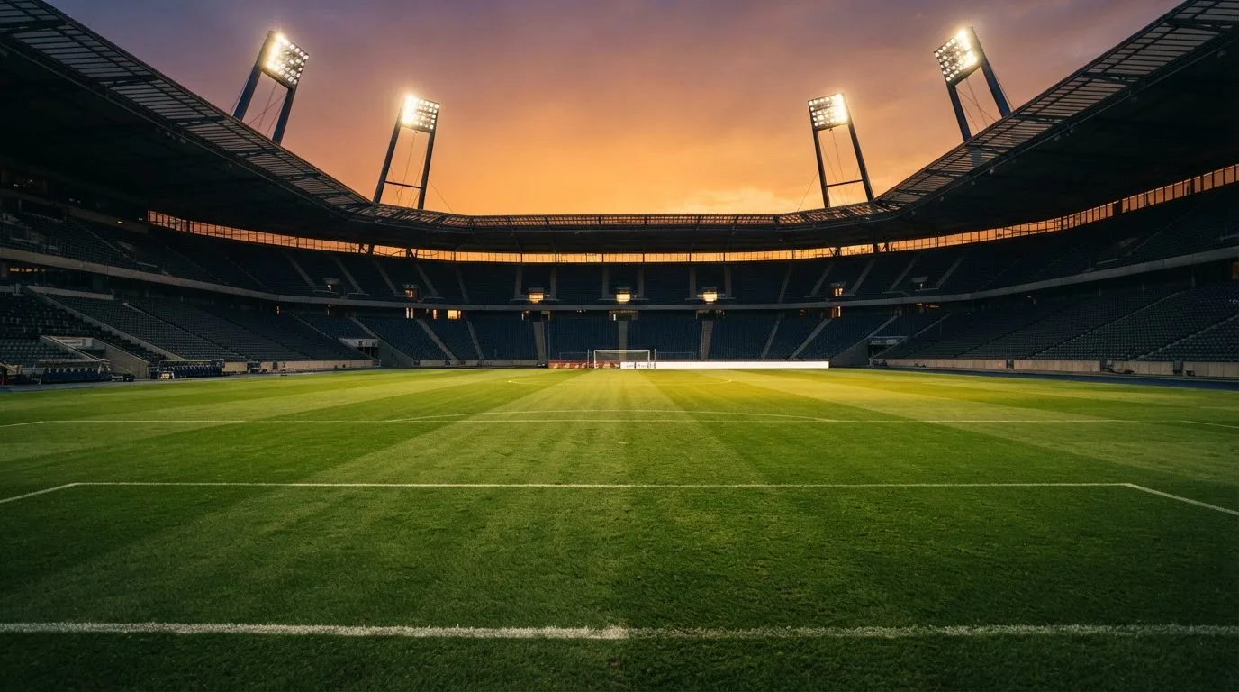 Un estadio de fútbol vacío con torres de iluminación al atardecer