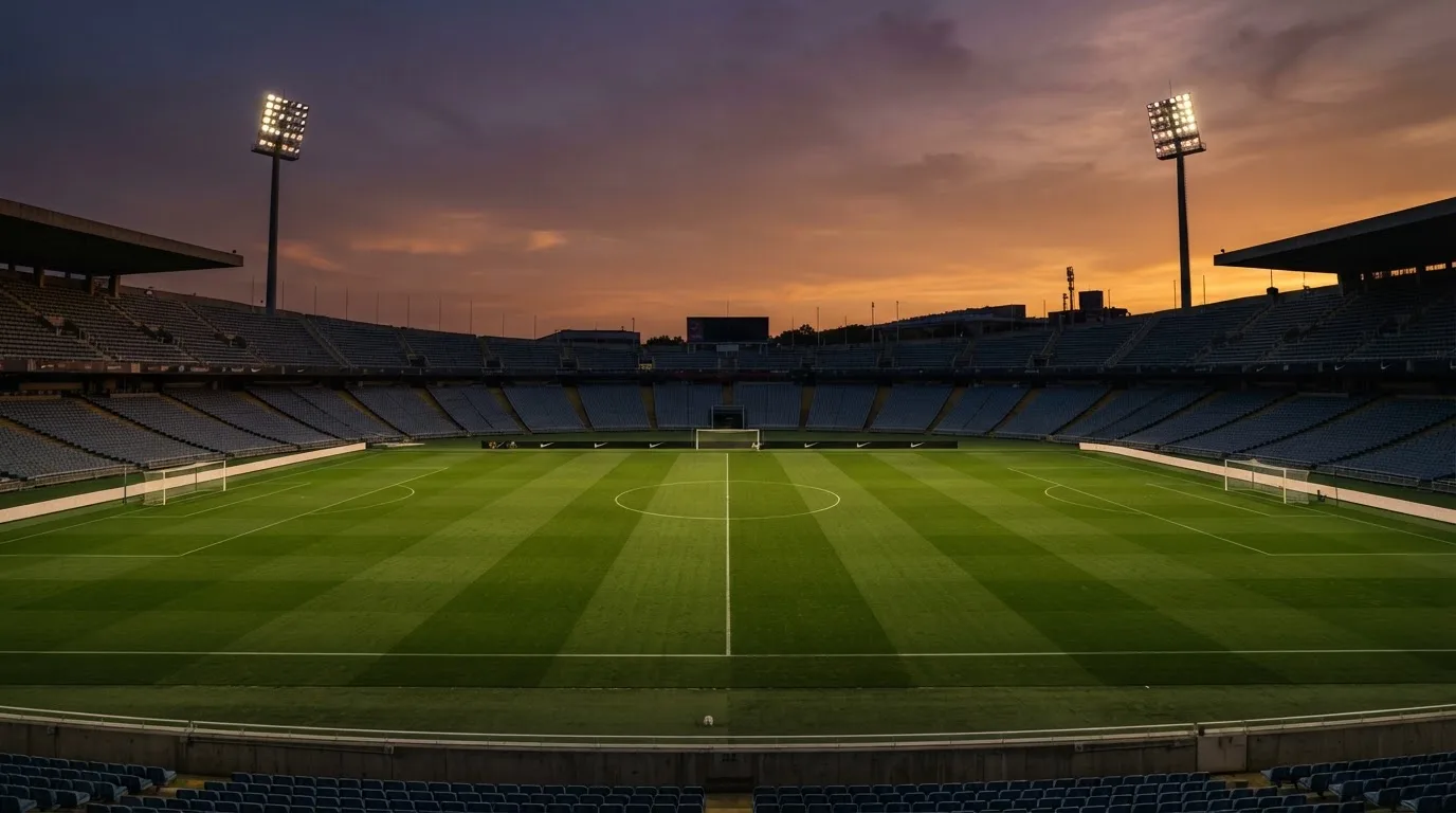 Un estadio de fútbol vacío con torres de iluminación al atardecer