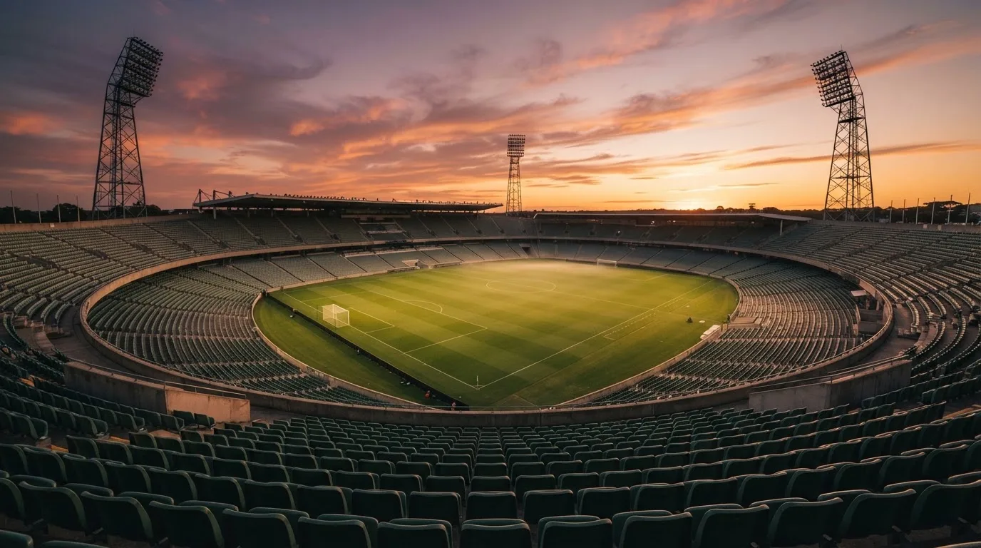 Un estadio de fútbol vacío con torres de iluminación al atardecer