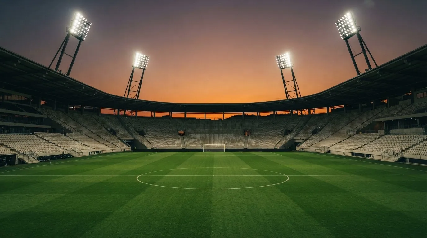 Un estadio de fútbol vacío con torres de iluminación al atardecer