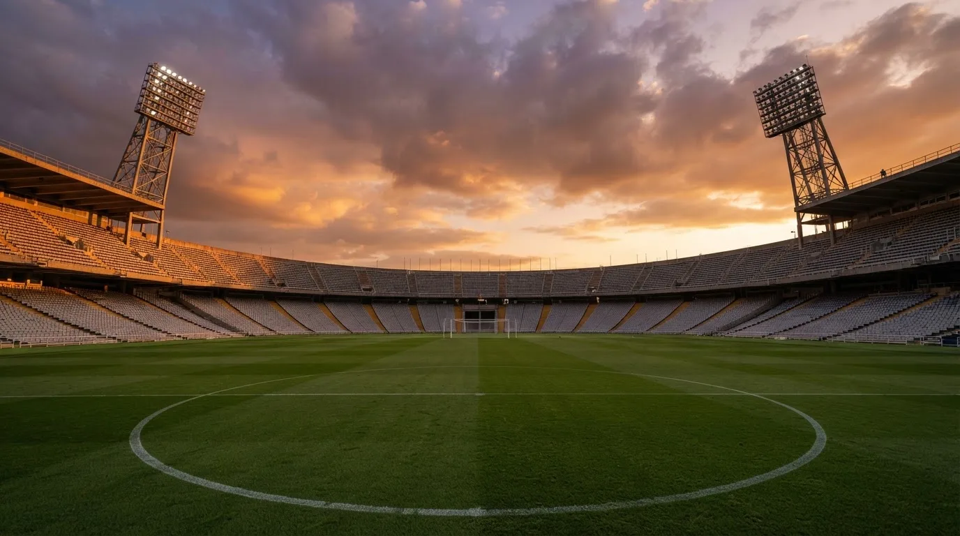 Un estadio de fútbol vacío con torres de iluminación al atardecer