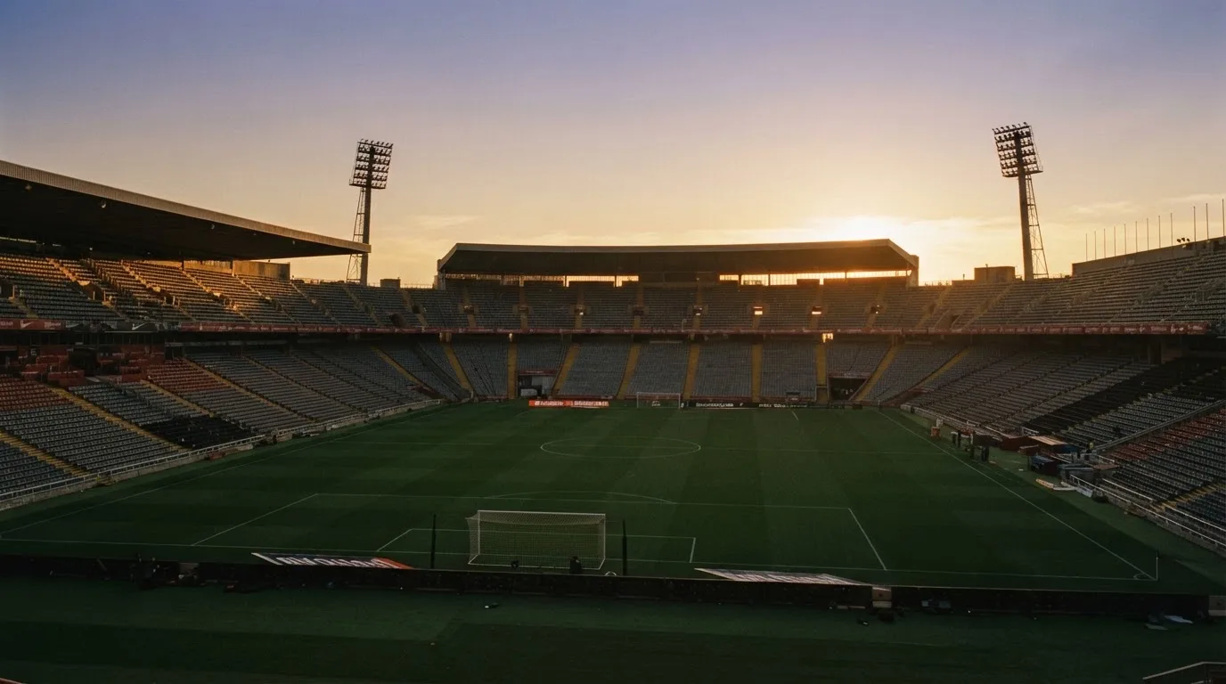 Un estadio de fútbol vacío con torres de iluminación al atardecer