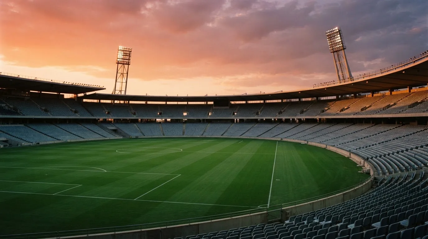 Un estadio de fútbol vacío con torres de iluminación al atardecer