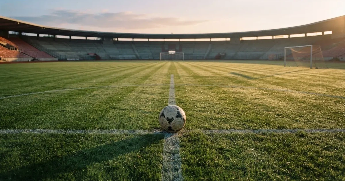 Un balón en el punto central de un campo de césped a la luz de la mañana