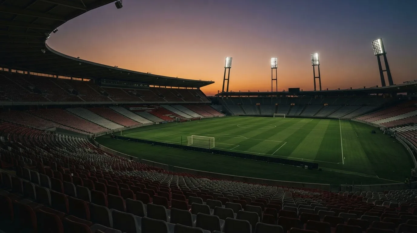 Un estadio de fútbol vacío con torres de iluminación al atardecer