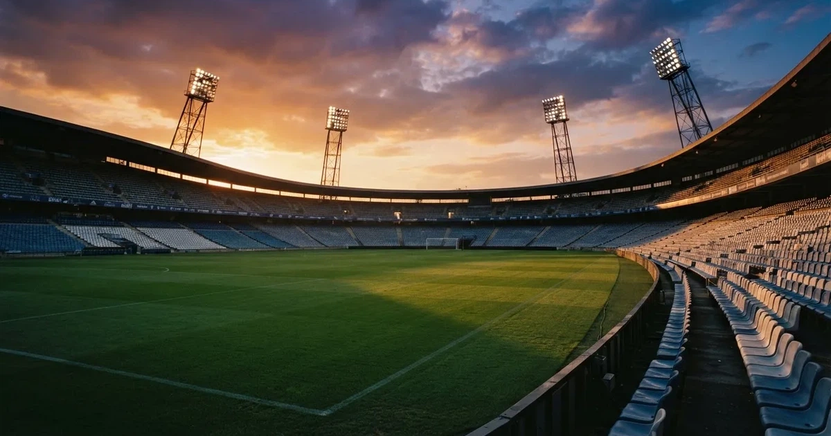 Un estadio de fútbol vacío con torres de iluminación al atardecer