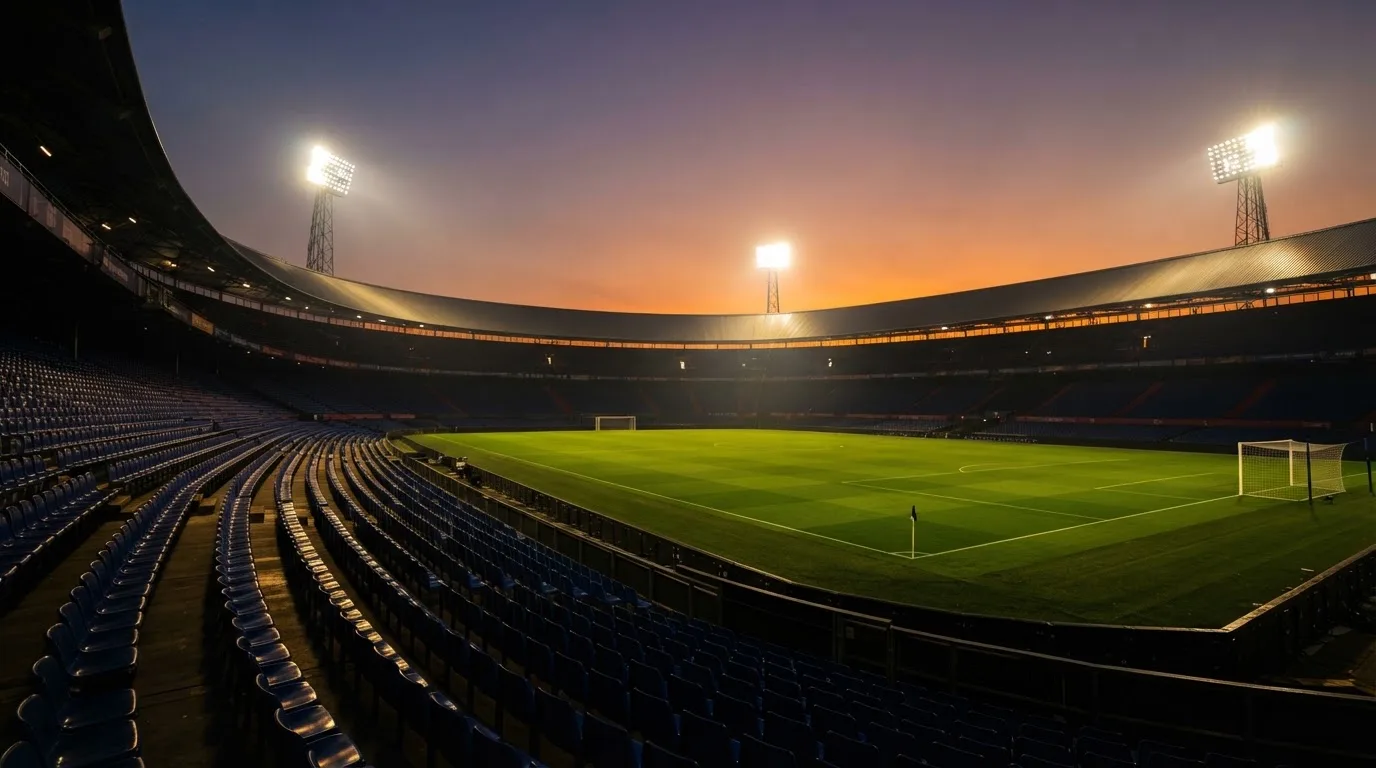 Un estadio de fútbol vacío con torres de iluminación al atardecer