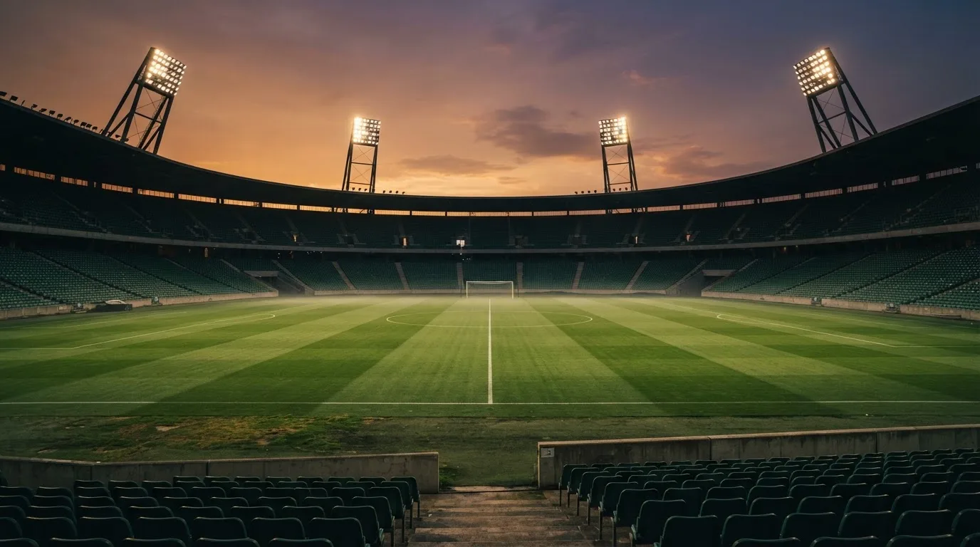 Un estadio de fútbol vacío con torres de iluminación al atardecer