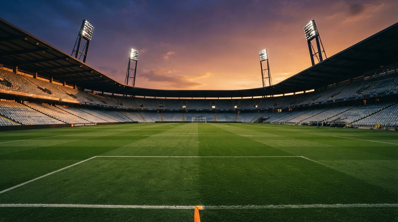 Un estadio de fútbol vacío con torres de iluminación al atardecer